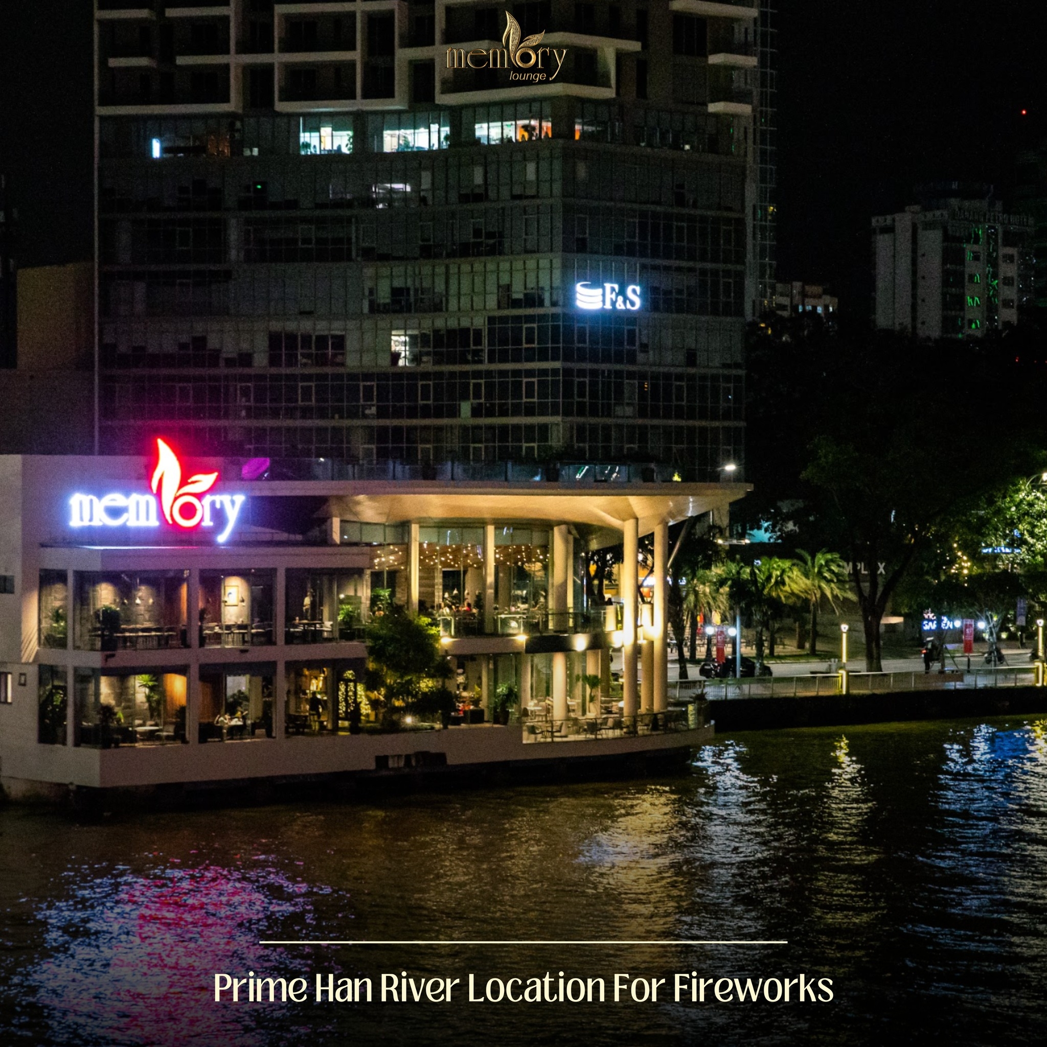 Brightly lit riverside Memory lounge building glowing at night beside the Han River, with tall city towers behind it