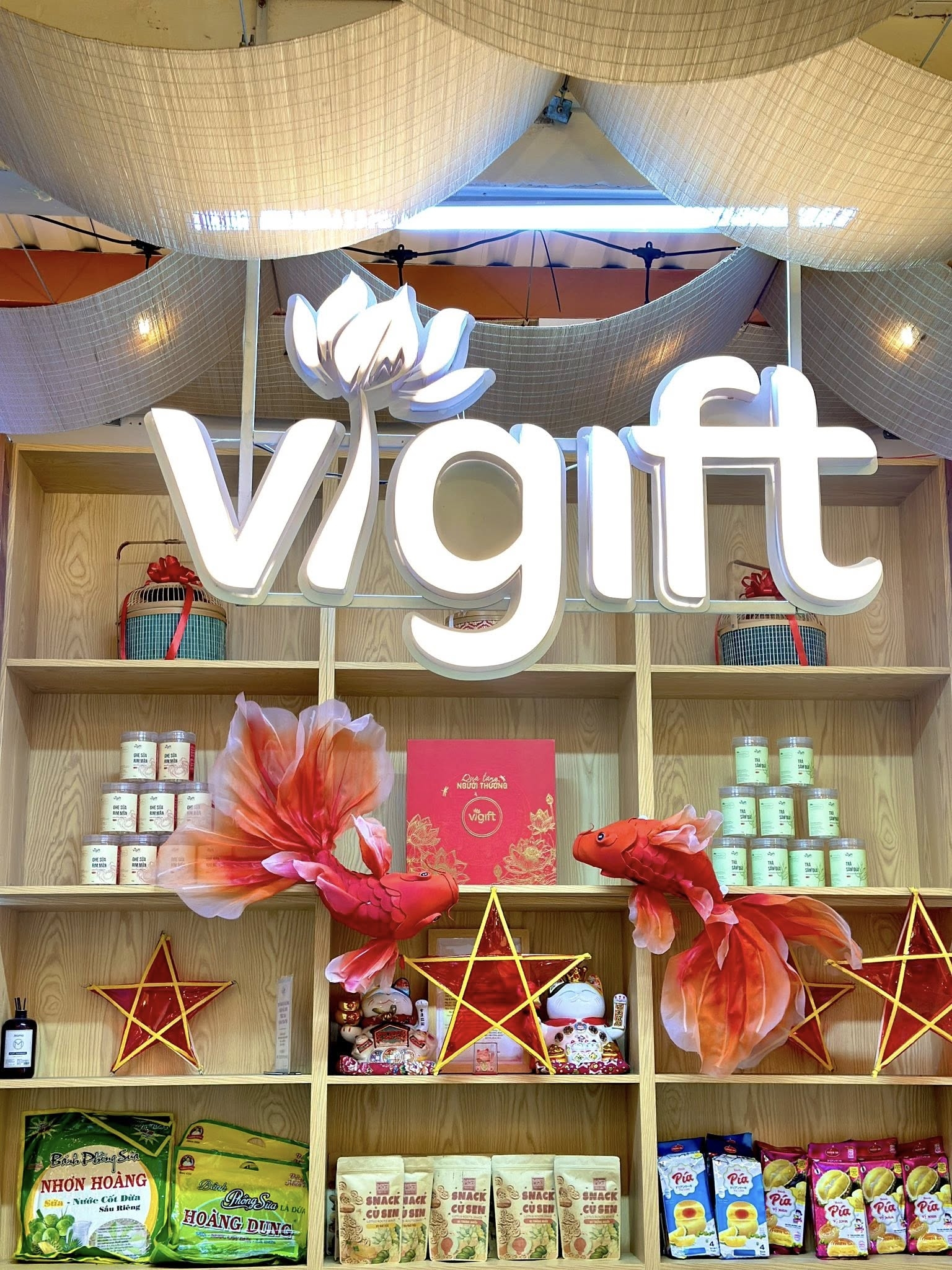 ViGift store display with a lit lotus logo above wooden shelves of products and red goldfish decorations