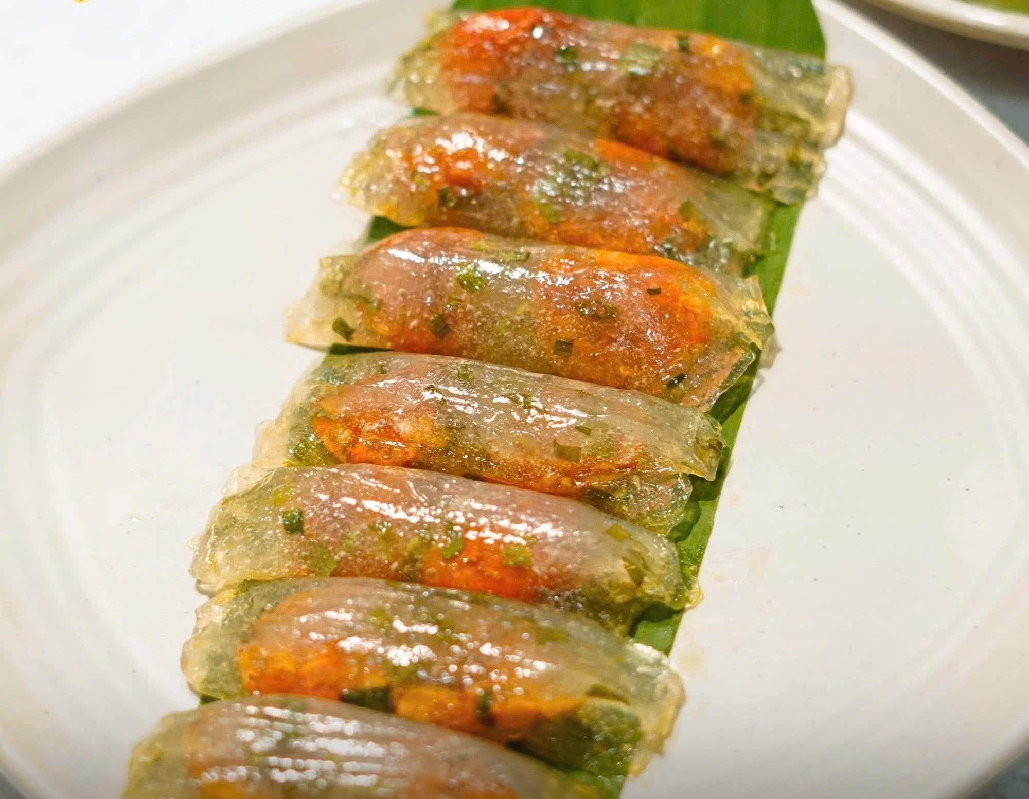 Row of translucent spring rolls filled with shrimp and herbs lined up on a banana leaf on a white plate