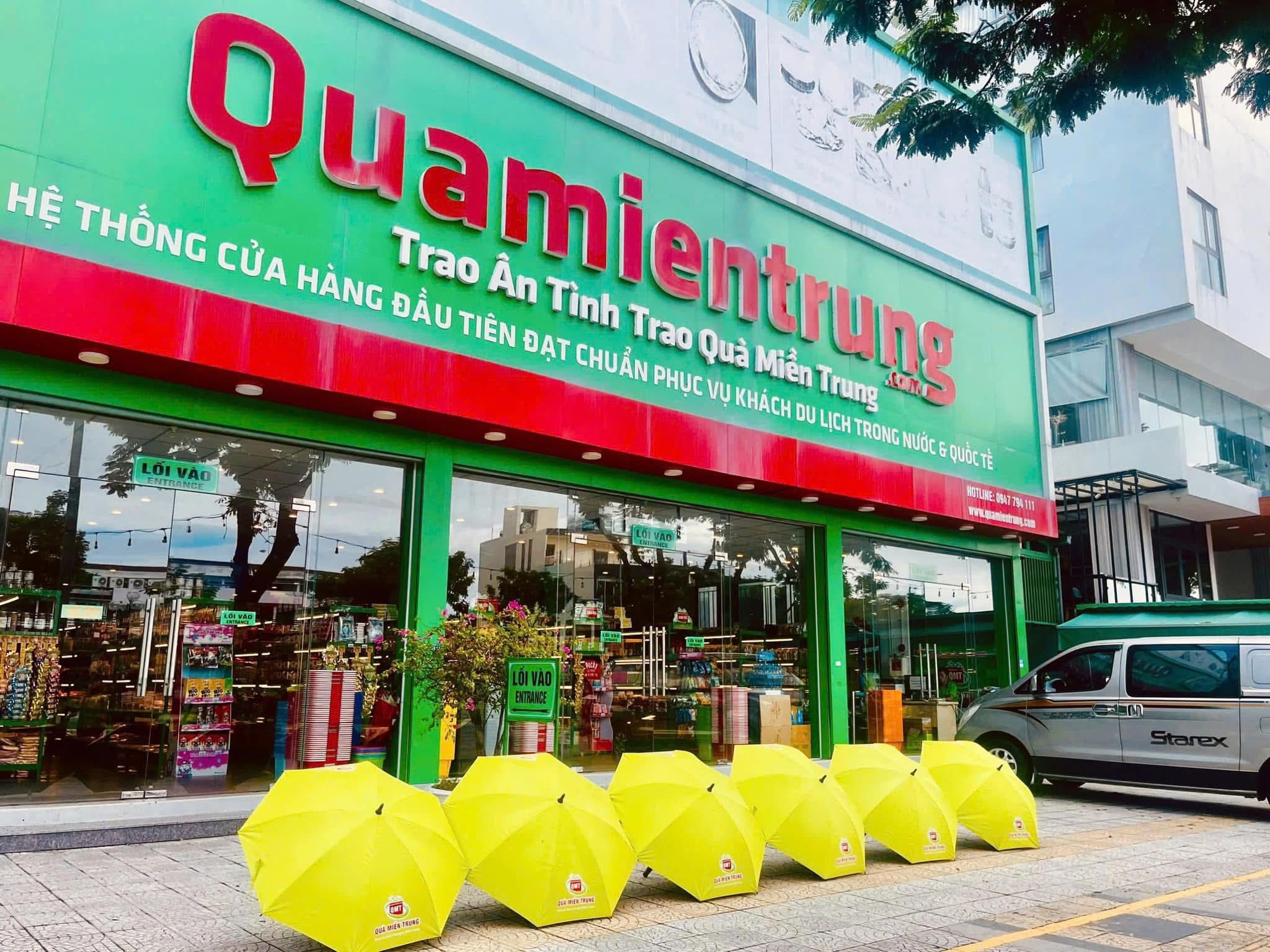Quamientrung gift store green storefront with red signage and a row of yellow umbrellas on the sidewalk