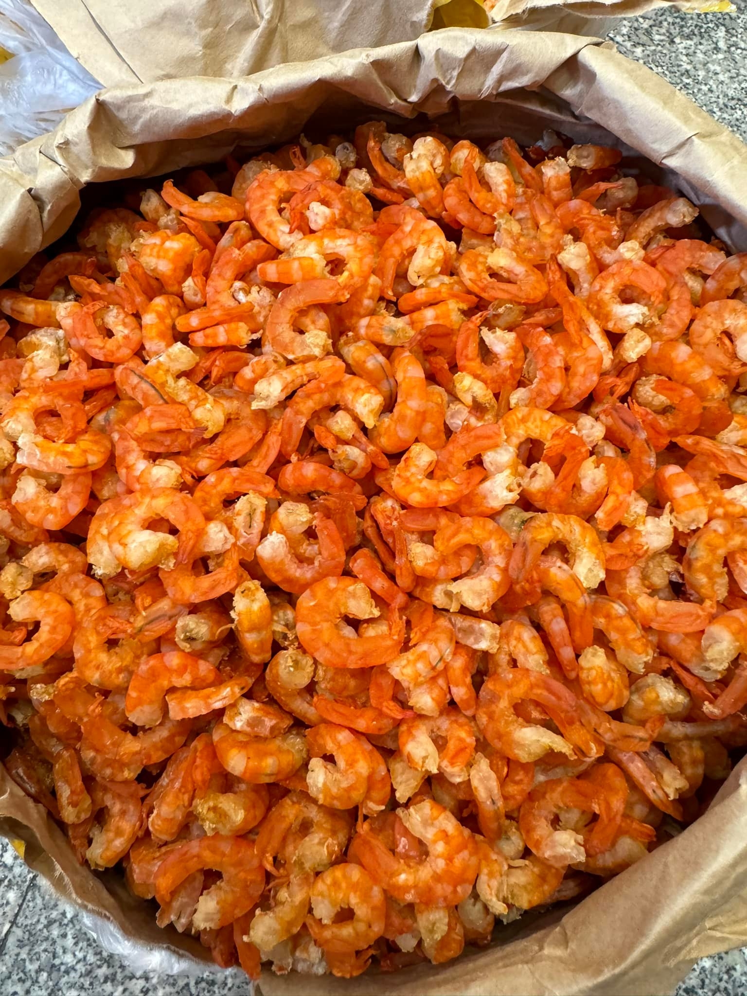 Open paper bag filled with orange dried peeled shrimp piled high, a classic Central Vietnam specialty