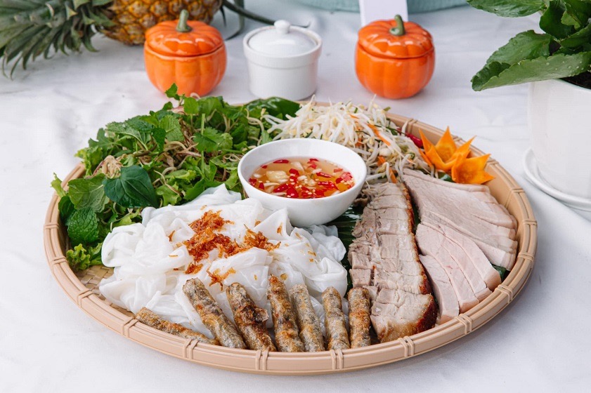 Soft bánh ướt rice sheets served with sliced pork, fresh herbs and a bowl of dipping sauce
