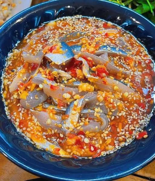 A wet-style plate of gỏi ướt — raw herring tossed with herbs, onion and a thick warm peanut-tapioca sauce