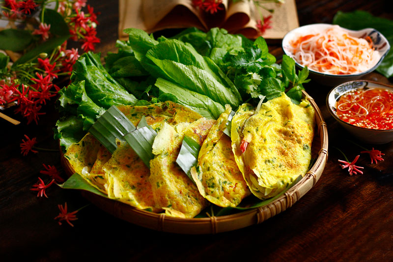 A golden, crispy turmeric-yellow Vietnamese bánh xèo pancake folded over shrimp and bean sprouts