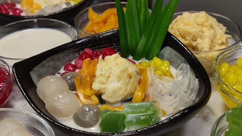 A glass of chè thái — tropical fruit, jelly and nata de coco in sweet coconut milk over ice.