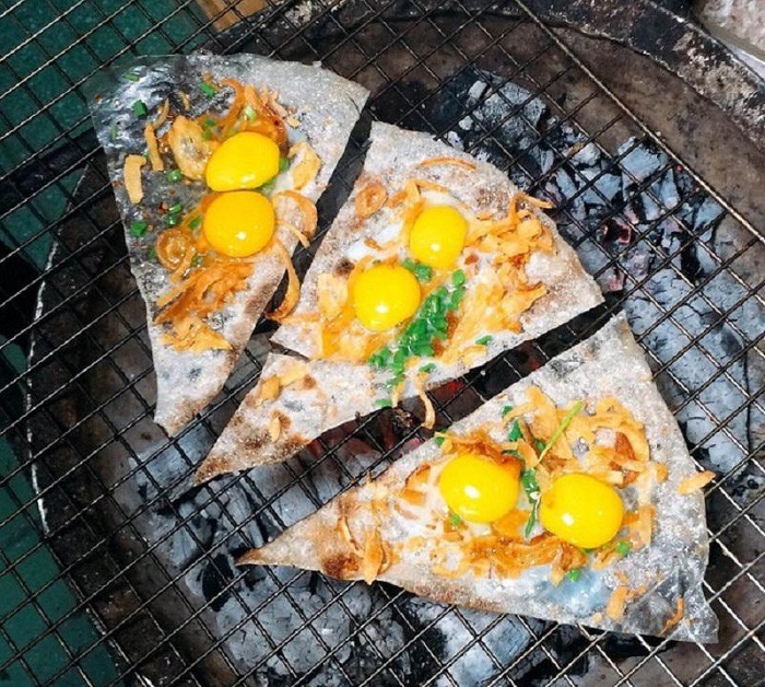 Bánh tráng kẹp grilling over charcoal — egg, dried floss and scallion crisping on the rice paper.