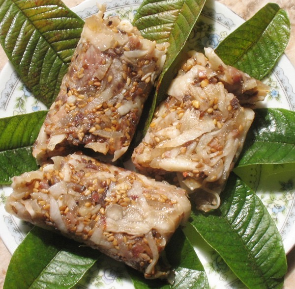 An opened tré log showing the loose nest of shredded pork, pork skin and galangal-flecked toasted-rice seasoning.