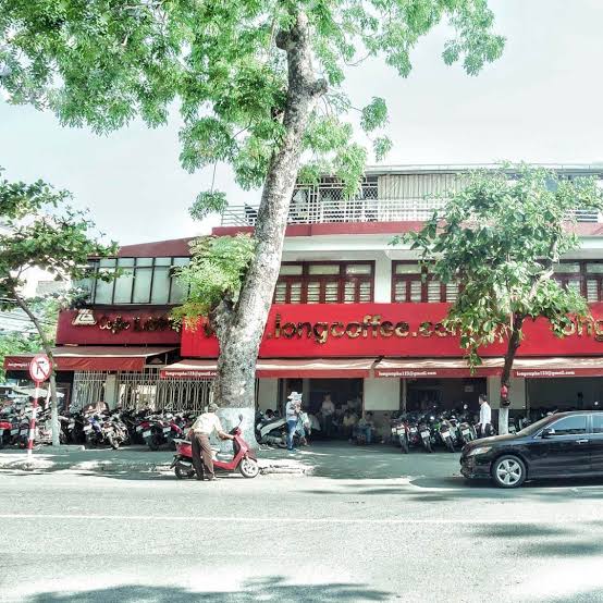 A laid-back streetside coffee spot with low plastic stools and an iced coffee — a common sight across Da Nang.