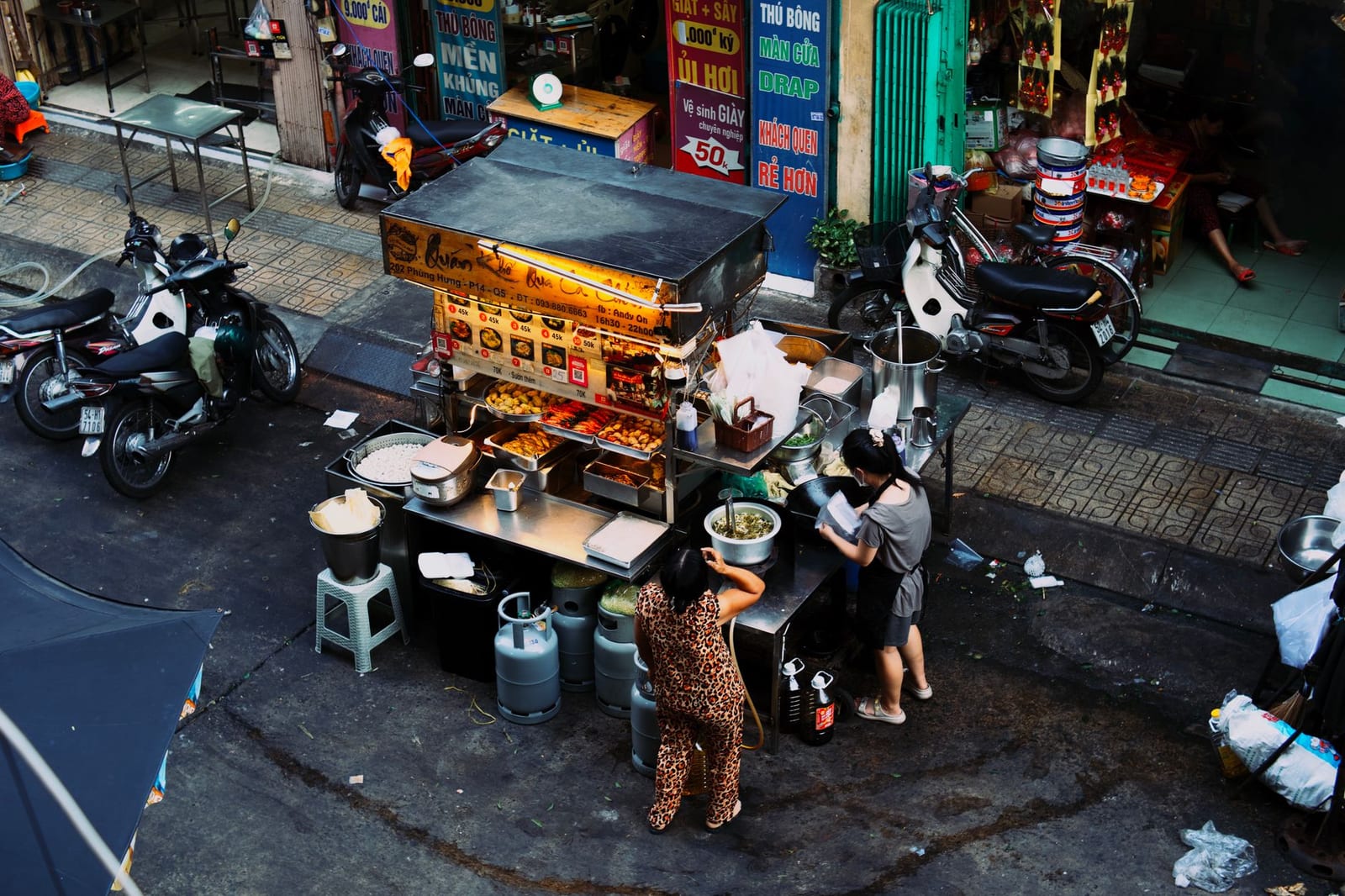 A busy local mì Quảng stall with low plastic stools and steaming pots