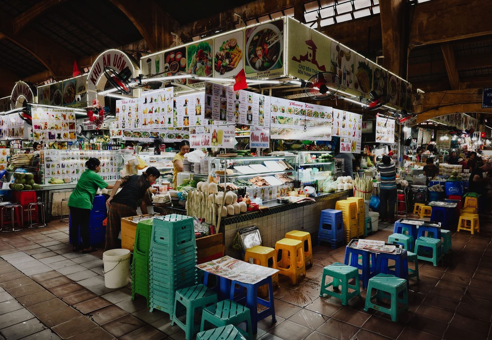 Food stalls and plastic stools inside Da Nang's Cho Con market with vendors and hanging signs