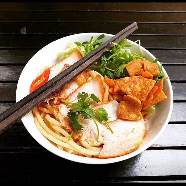Close-up of cao lầu's firm, square-cut noodles and crispy fried squares.