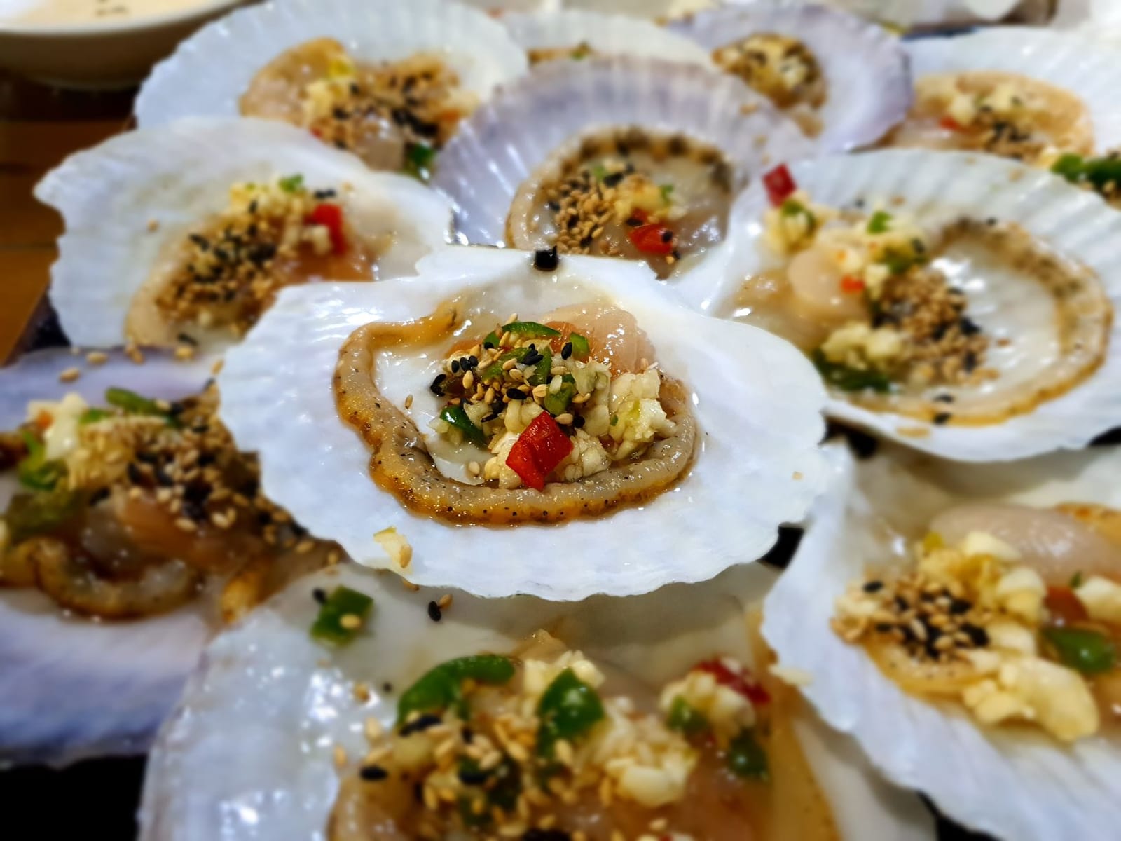 Grilled scallops topped with scallion oil and crushed peanuts on the half shell.