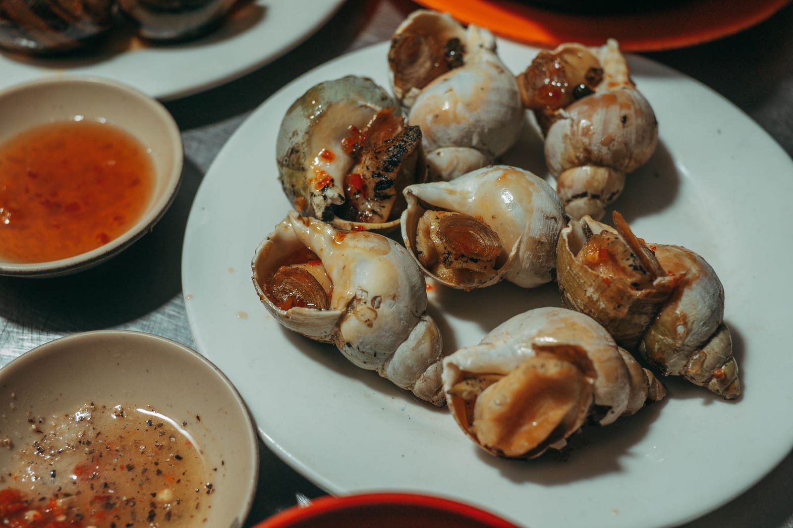 A plate of lemongrass-and-chili snails (ốc hút) with a lime-salt dipping bowl.