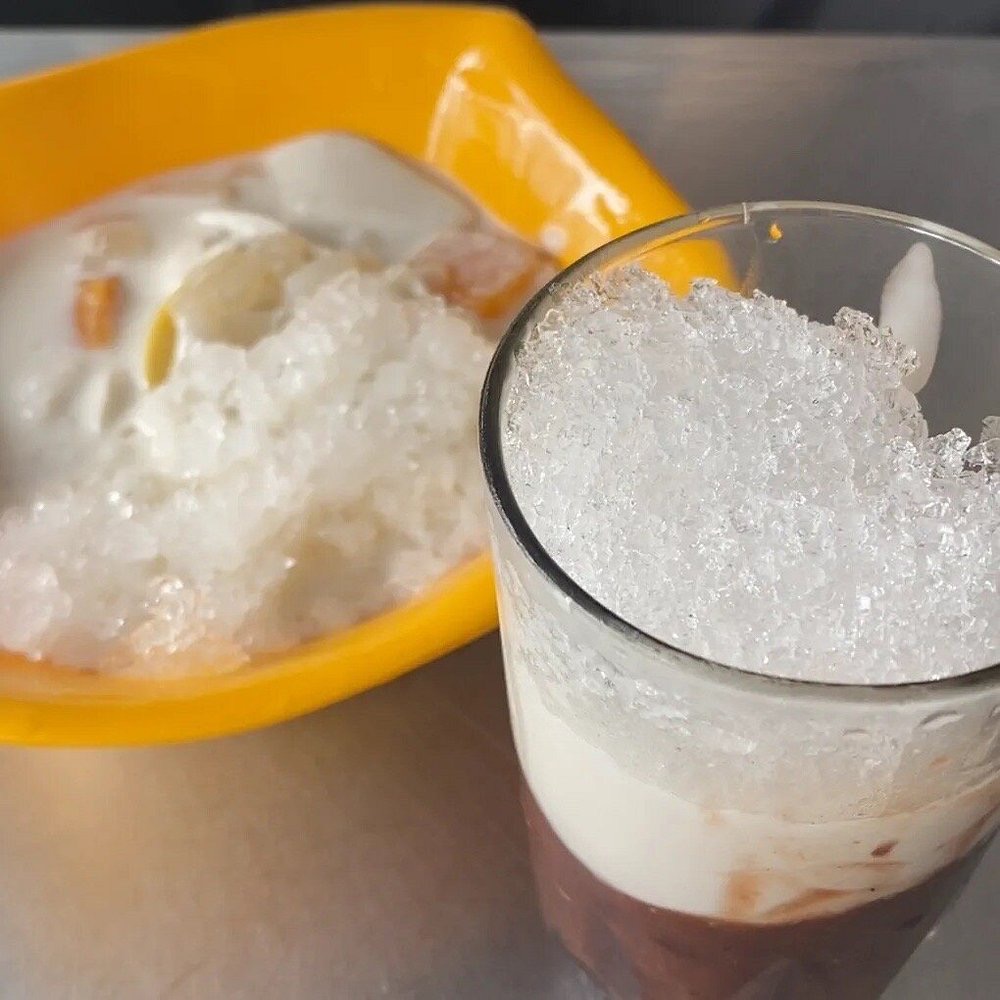 Chè with green beans, red beans and coconut milk in a clear glass