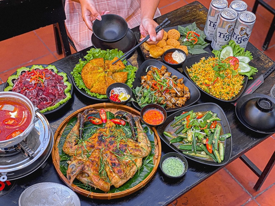 Locals sharing iced beer and grilled food at a Da Nang sidewalk quán nhậu at dusk