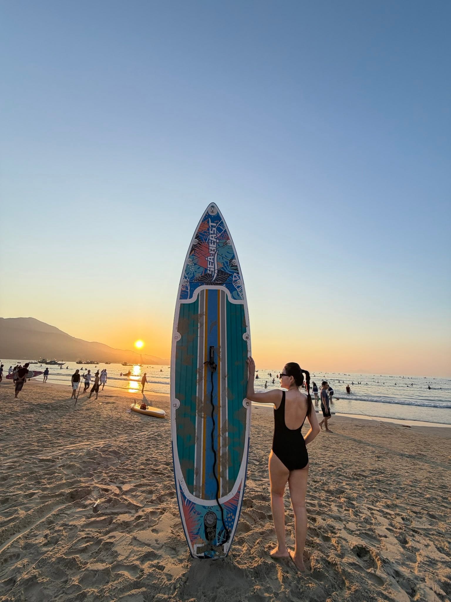 A lone paddleboarder in silhouette on calm sea at sunrise.