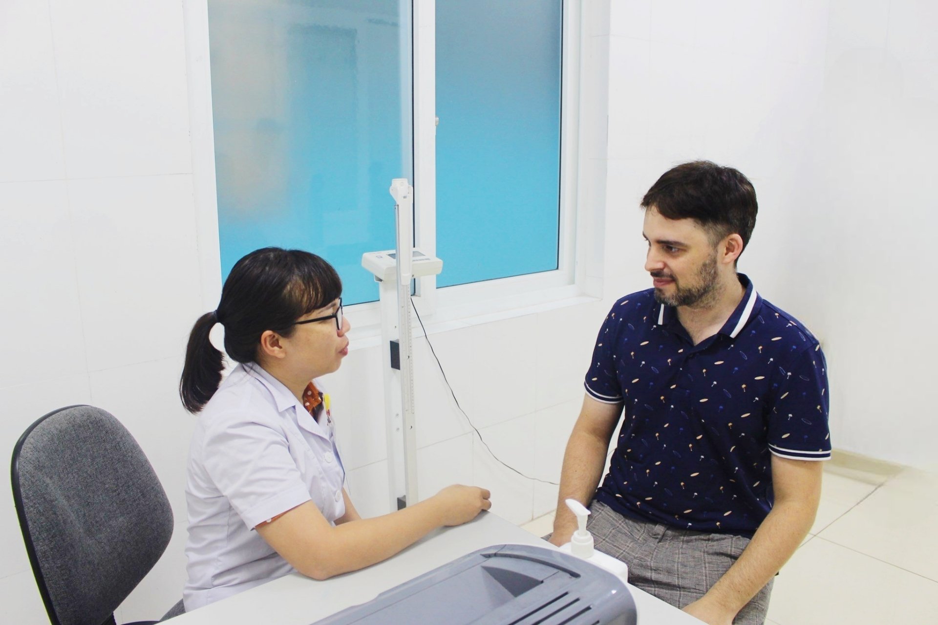 A doctor consulting with a patient in a bright modern clinic room in Da Nang