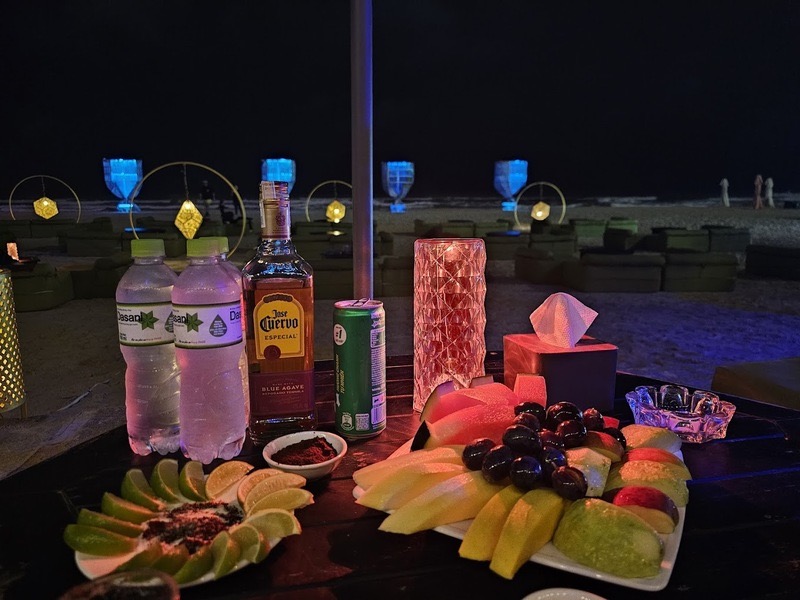 Drinks and a fruit platter set up on a Da Nang beach at dusk.