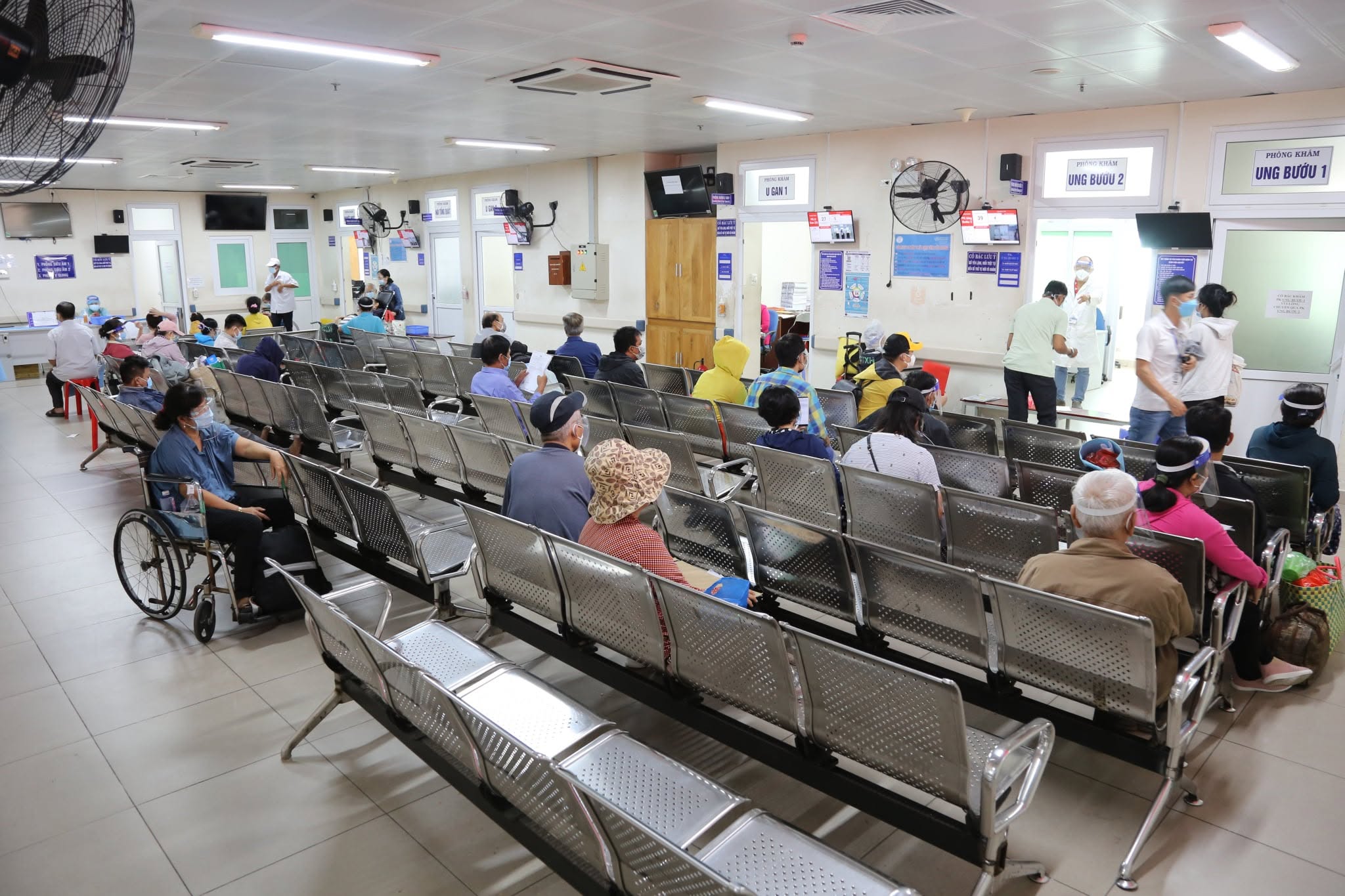 Patients waiting on benches in a busy hospital outpatient area in Da Nang