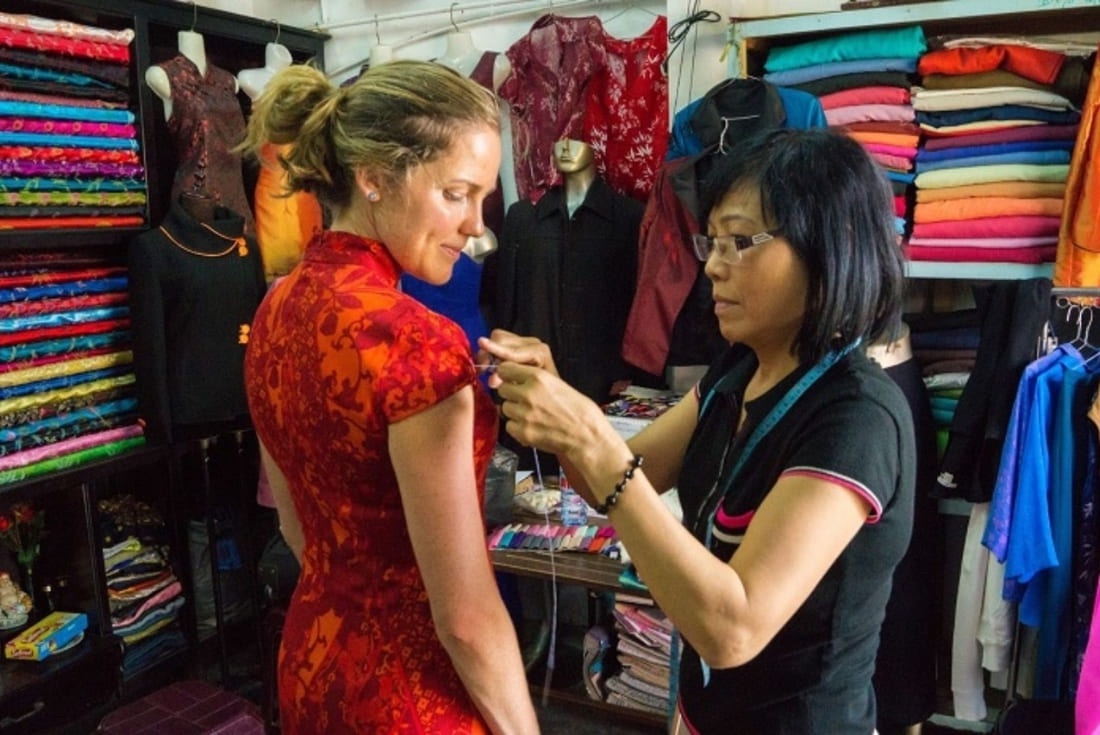 A fitting in progress: a tailor pins a custom áo dài on a customer in Hội An.