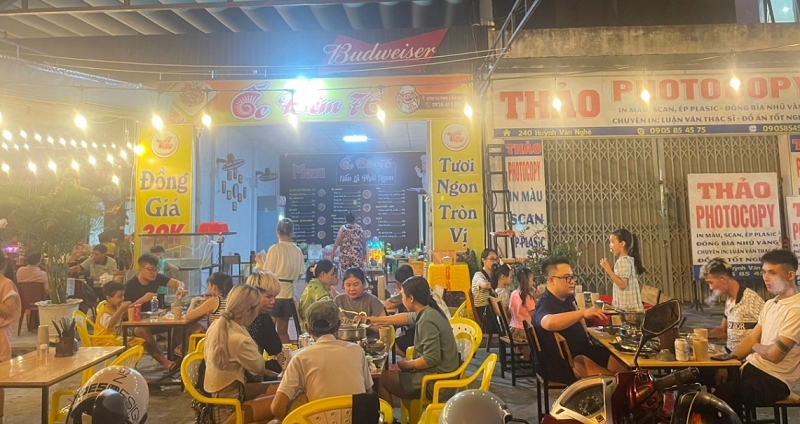 Diners gathered on low plastic stools at a lamplit street-side stall — the heart of Da Nang's nhậu culture.