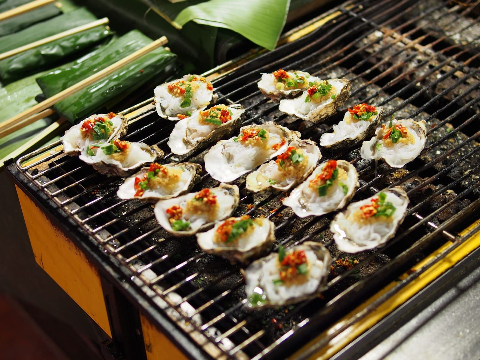 Grilled oysters with scallion oil and crushed peanuts — a seafood dish that travels well for delivery.