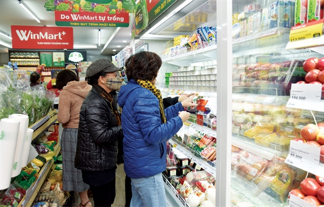 WinMart+ mini-supermarket interior — WinMart+ logo visible top-left, fresh produce section with VinEco-grown vegetables and chilled goods.