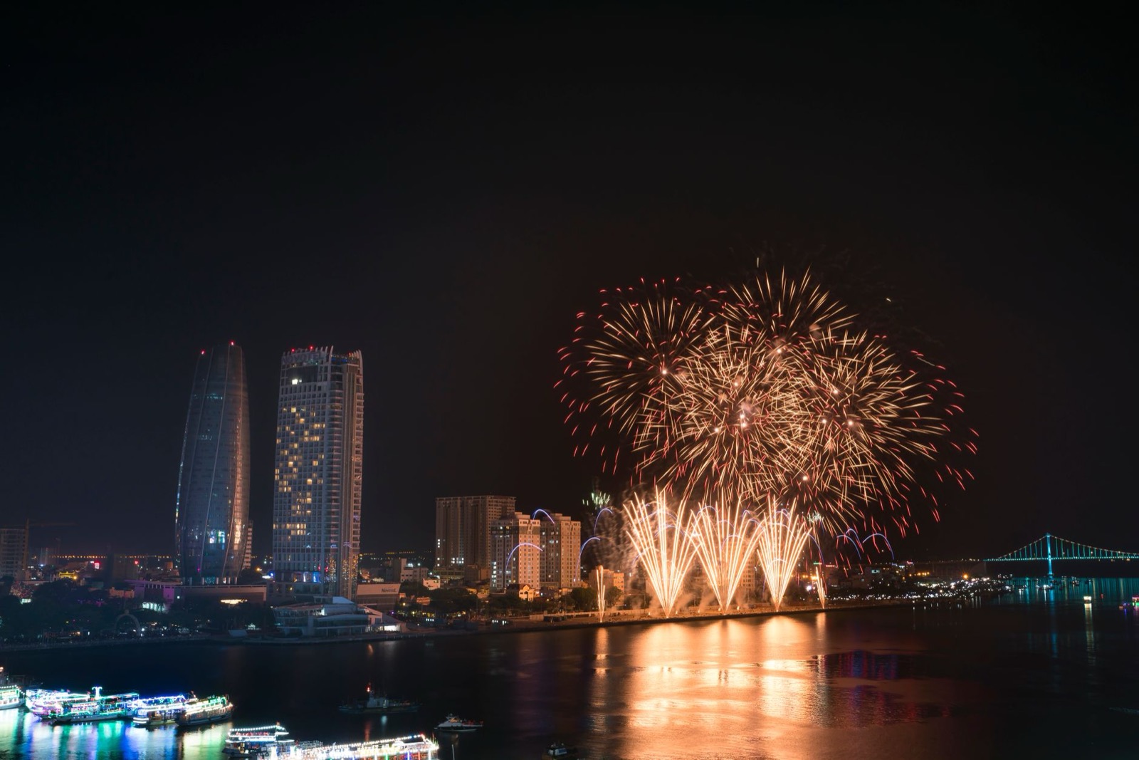 Fireworks over the Han River with Da Nang's skyline and riverboats during the International Fireworks Festival