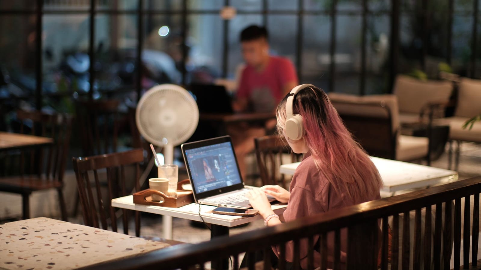 A near-empty cafe late at night, with two people working on laptops under warm lights.