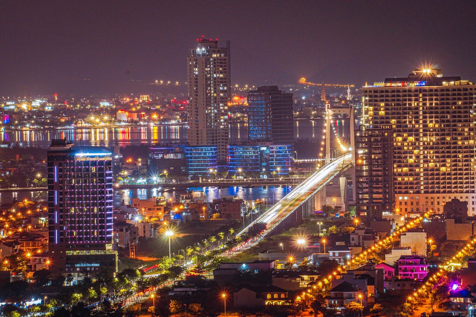 Da Nang lit up at night, with an illuminated bridge crossing the river.